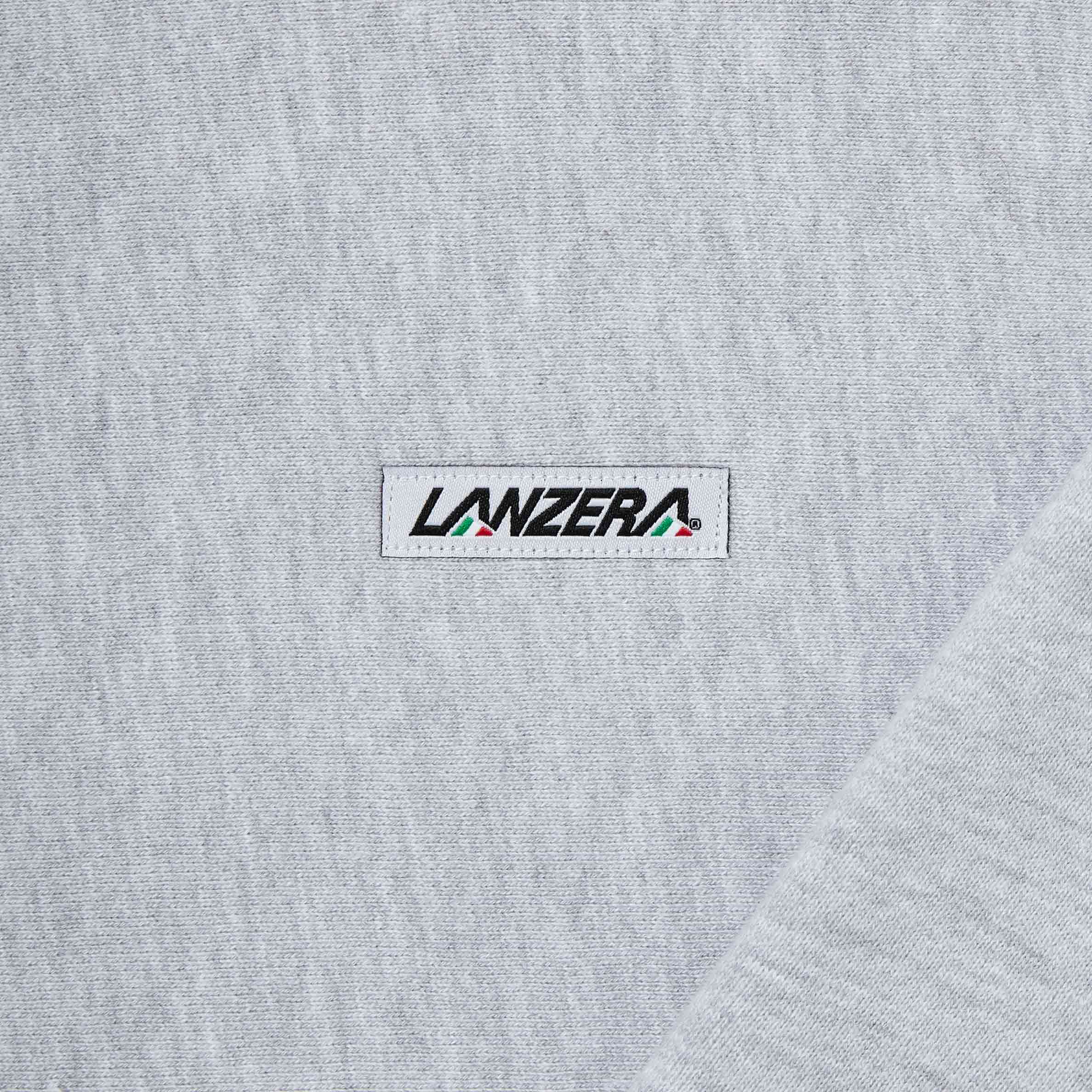 Close-up of the Lanzera Club Crewneck's embroidered logo patch, stitched onto soft grey heather fabric. A subtle nod to football heritage with a refined, understated aesthetic.