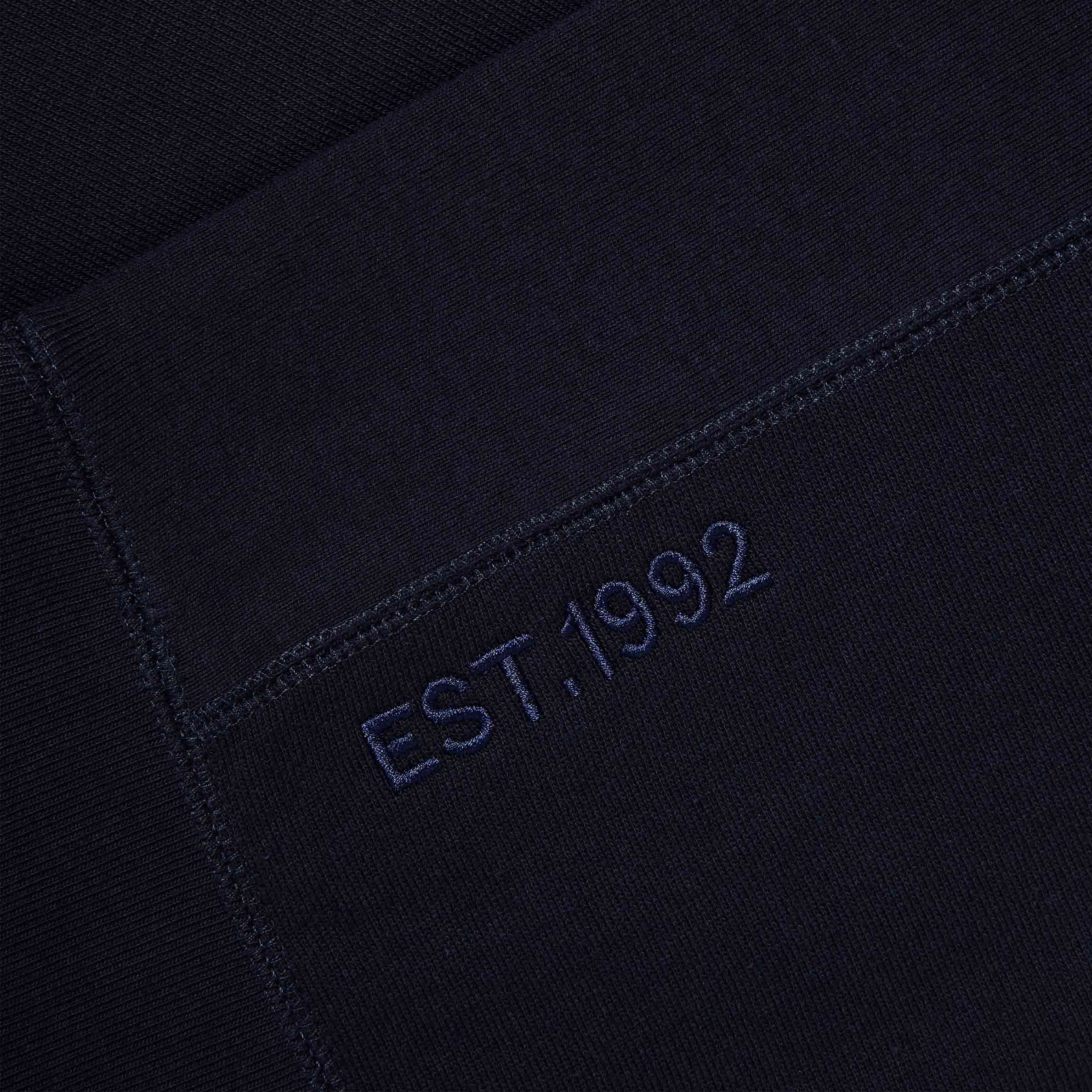 Detailed view of the 'EST. 1992' tonal embroidery on the Lanzera Club Hoodie in Navy Clásico, celebrating the brand’s football heritage.