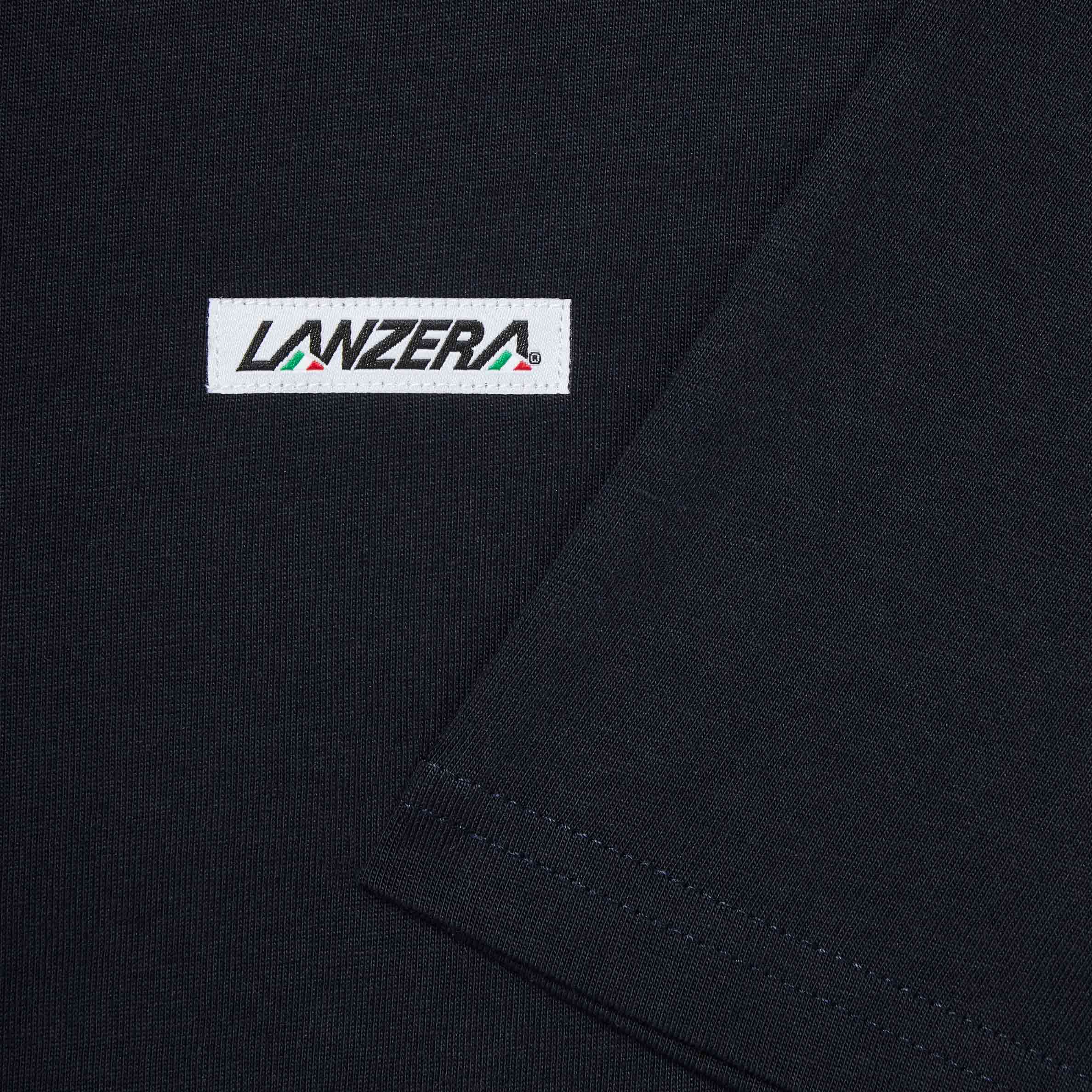 Close-up of the woven Lanzera logo patch on the Club Tee in Navy Clásico. The embroidered patch, stitched onto the high-quality cotton fabric, adds a subtle yet distinct branding touch.