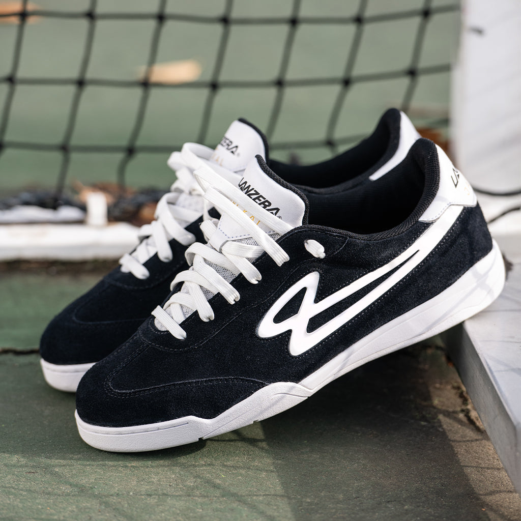 Lanzera Jackal black suede sneakers resting on an outdoor court, highlighting the premium suede upper, white branding, and non-marking sole for futsal and streetwear versatility.