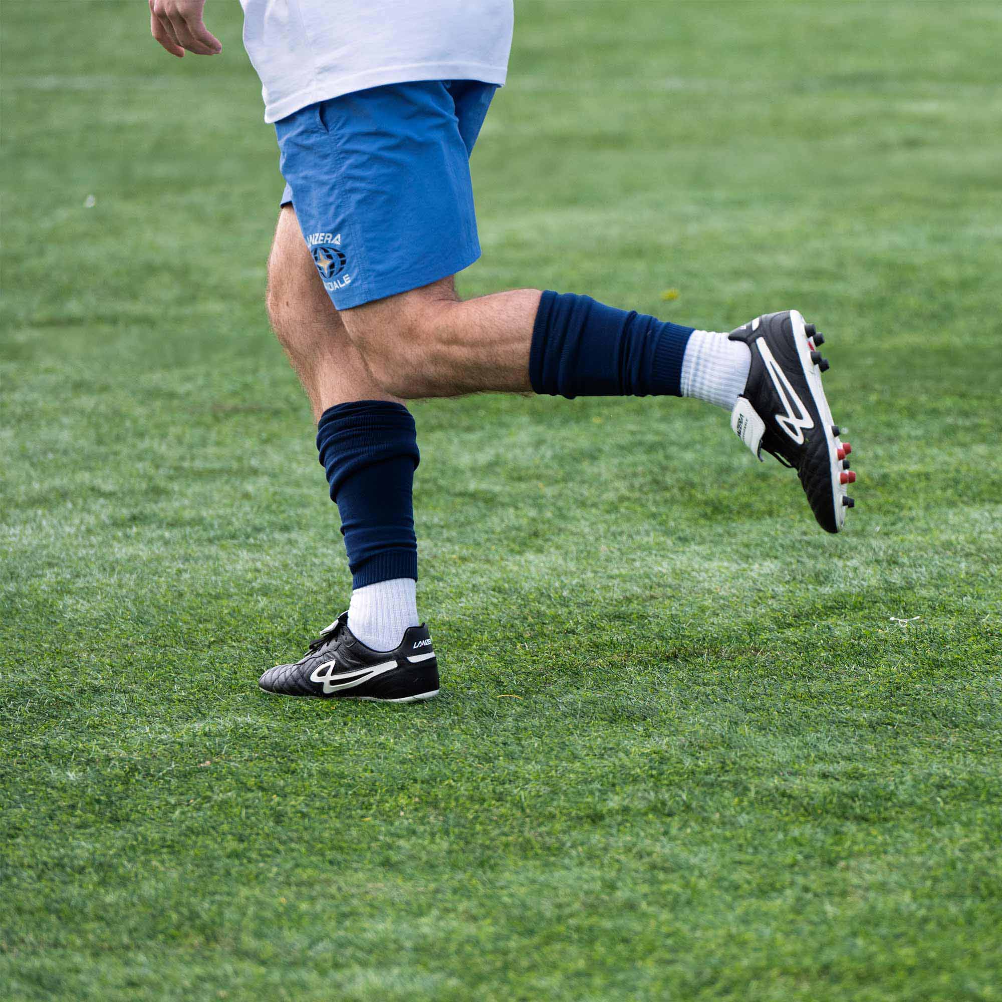 Player wearing Lanzera Professionale cleats, running during match play on a grass field.