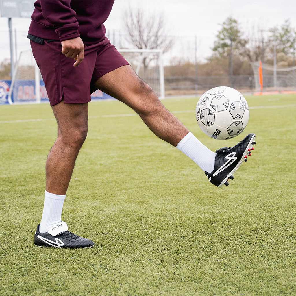 A player juggling a soccer ball in Lanzera Professionale cleats, emphasizing the barefoot-like touch of the K-leather upper and the natural movement support from the lightweight firm ground soleplate.