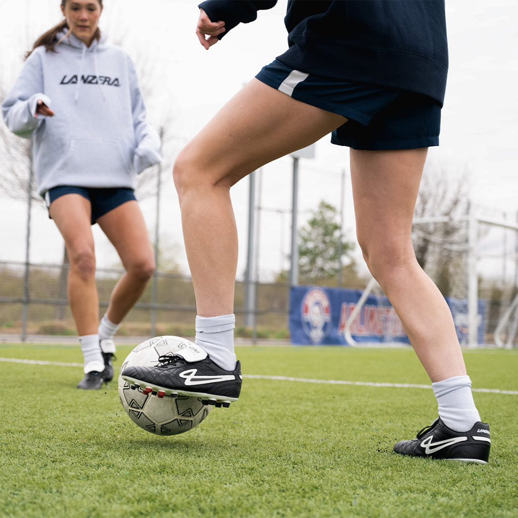 Close-up of a player wearing Lanzera Professionale soccer cleats while controlling a ball, highlighting the precise touch, responsive K-leather upper, and firm ground stud configuration.